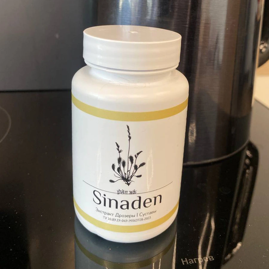 Баночка с капсулами Синаден стоит на столе на фоне электрического чайника