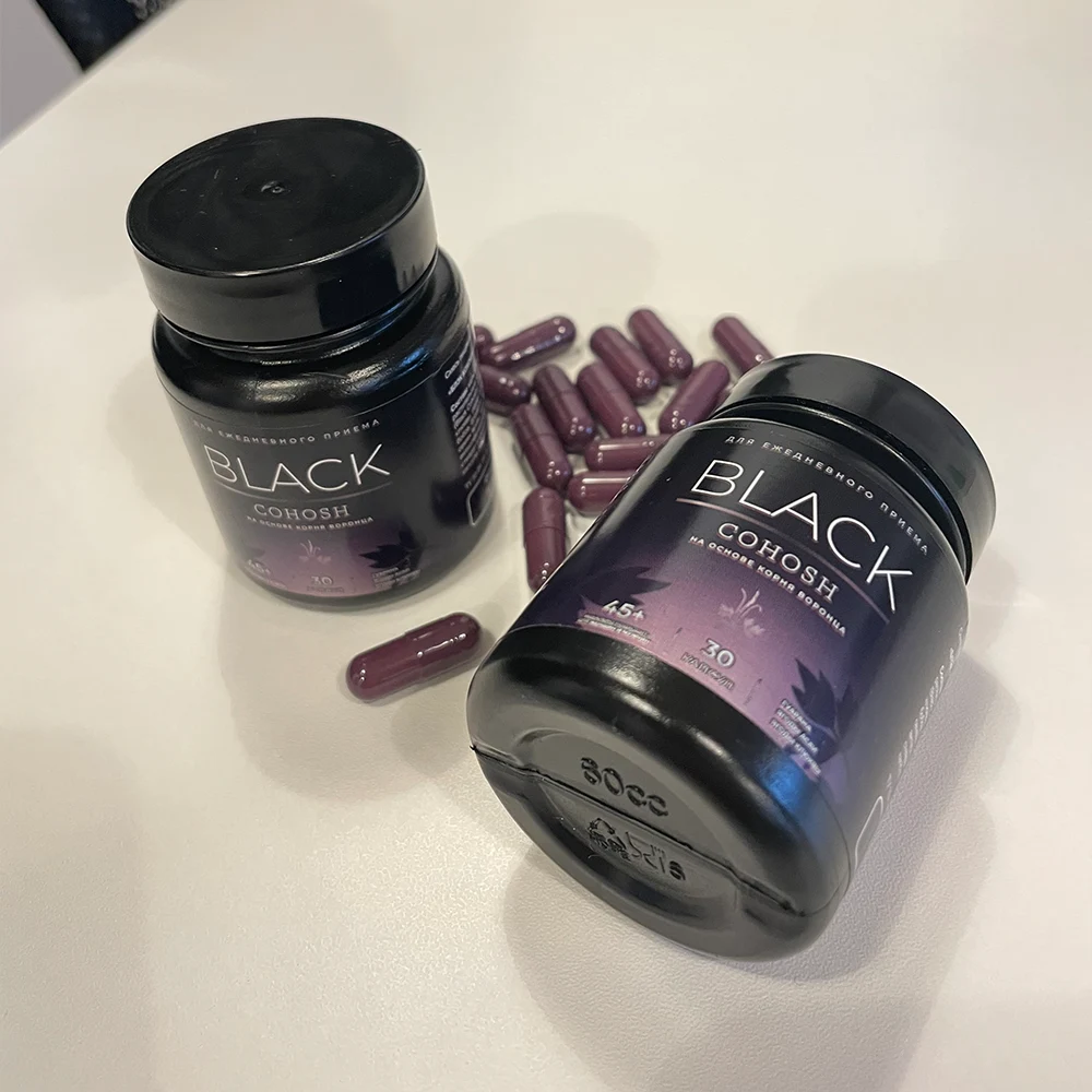 Две баночки Чёрного Кохоша на столе и рассыпанные капсулы