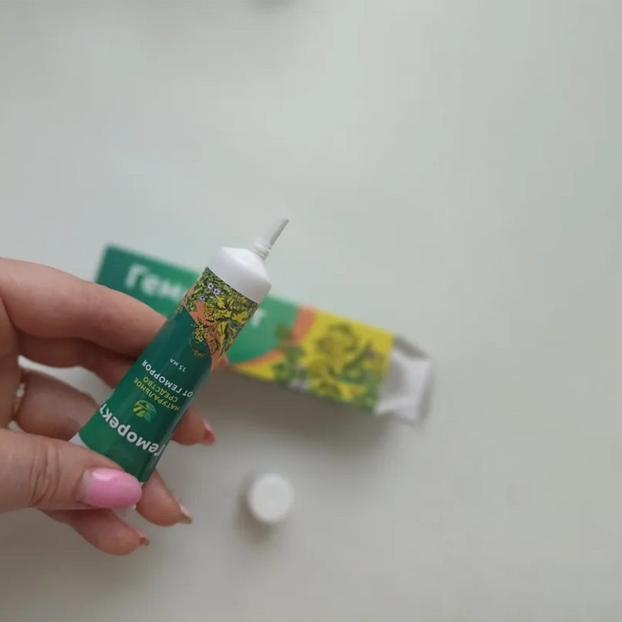 Женская рука держит тюбик с мазью Геморект