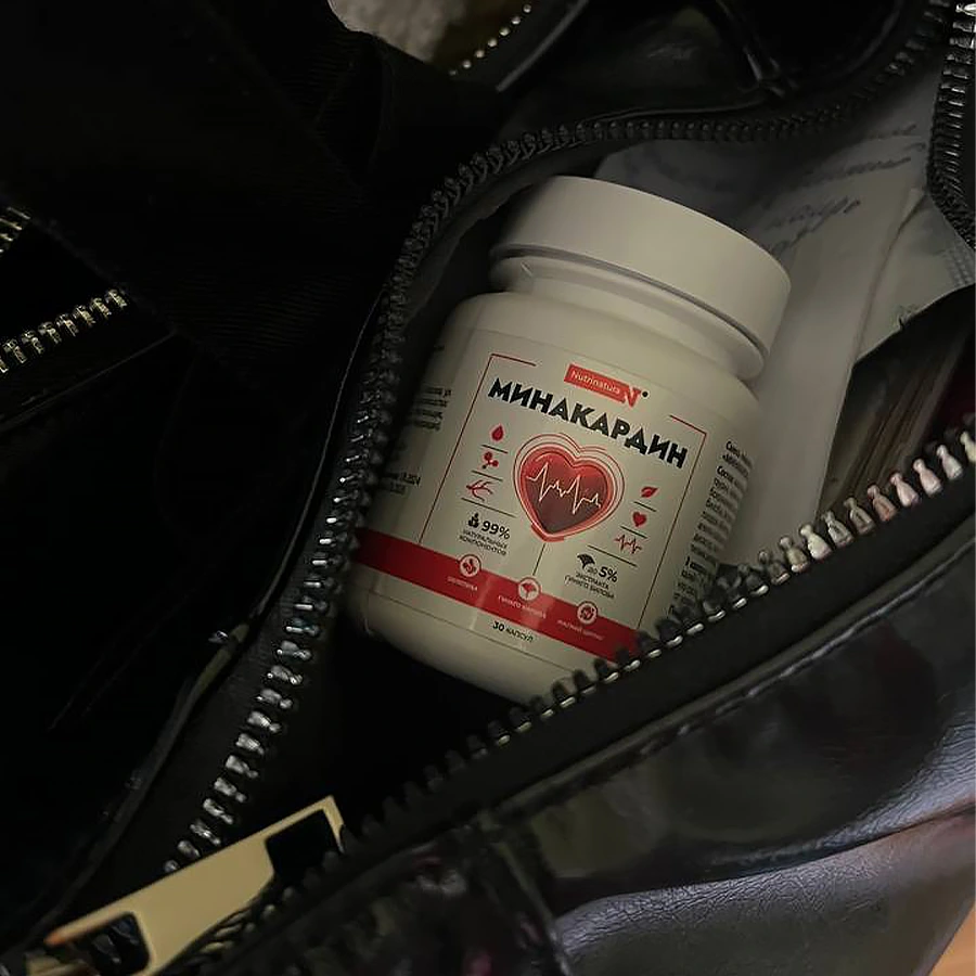 Баночка с капсулами Минакардин лежит в чёрной кожаной сумке