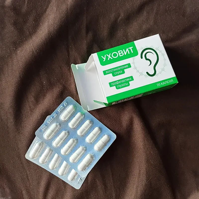 Упаковка и два блистера с капсулами Уховит лежат на коричневой ткани