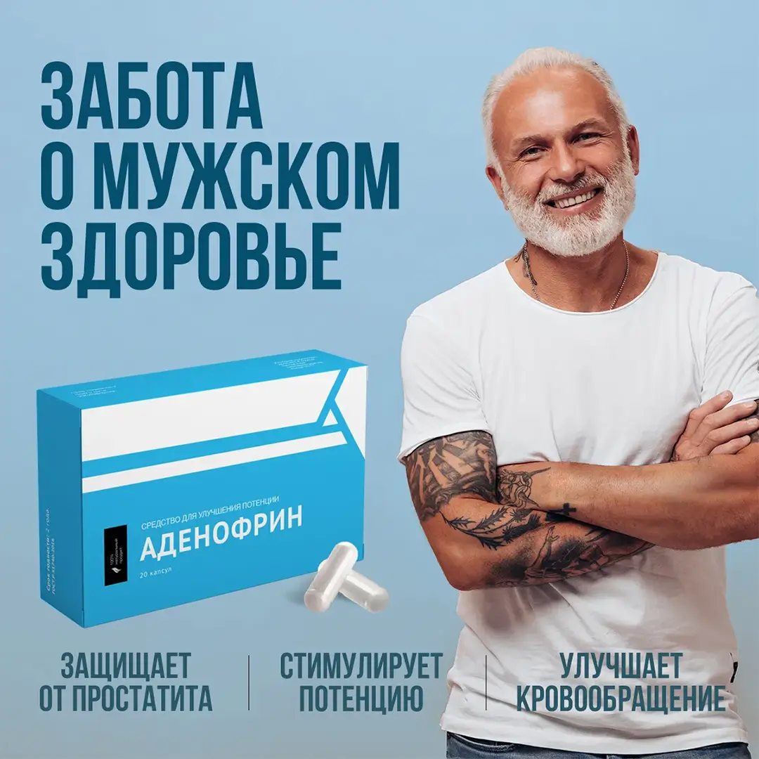 Татуированный седой мужчинка в белой футболке улыбается глядя в экран рядом с упаковкой капсул для потенции Аденофрин