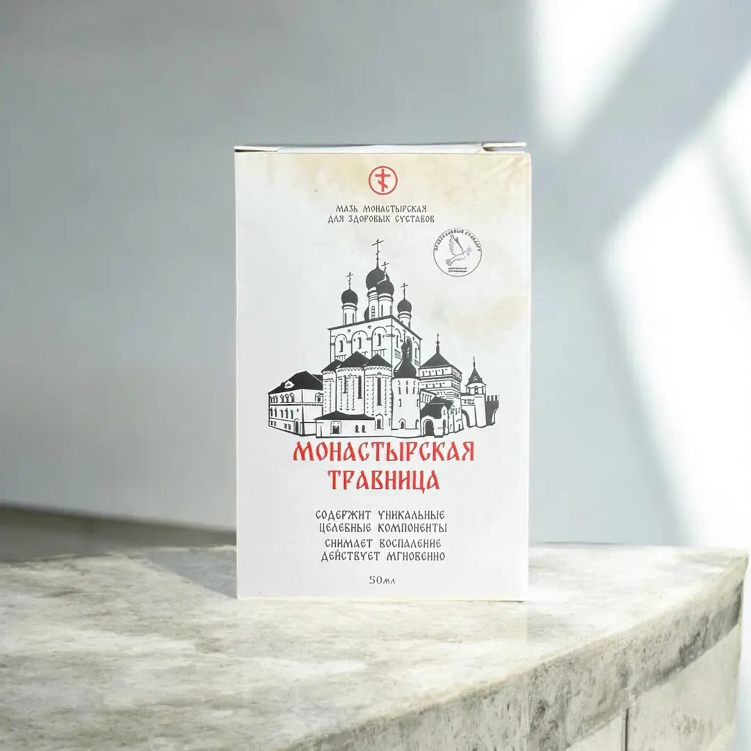 Упаковка мази Монастырская травница для здоровых суставов на светлой поверхности, белая коробка с изображением монастыря и красным логотипом